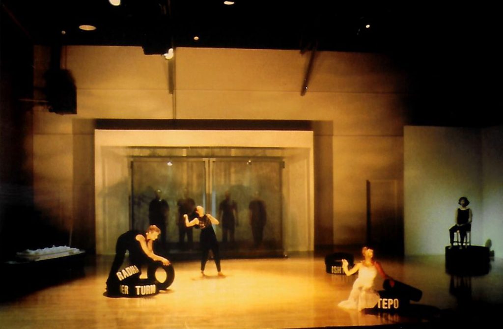DCK, lit stage, rolling tire, 2 dancers, Young-Ruth